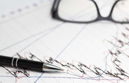data analyzing in stock market: eyeglasses and a penの写真素材