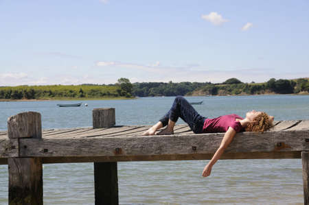 Pretty girl lying and relaxing on landing stage in Brittany, France on a sunny day.の写真素材