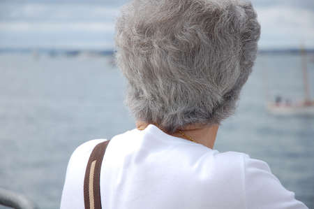 Grey haired senior woman looking at the atlantic oceanの写真素材