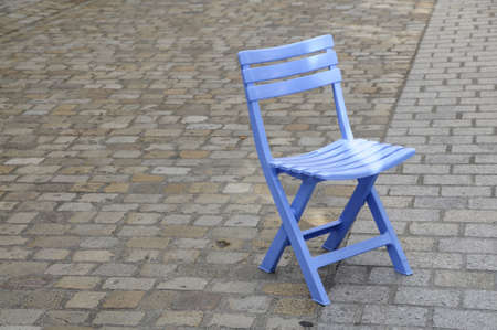 Shot of blue folding chair on cobbled pavementの写真素材