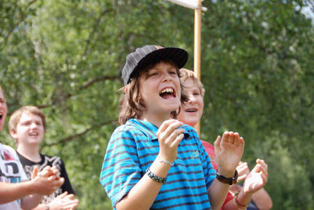 MITTERSILL, AUSTRIA - JUL 4: Unidentified Children cheering for participants of the Water fun Event Erdinger Sautrogrennen on July 4, 2010 at the Zierteich in Mittersill, Austriaのeditorial素材