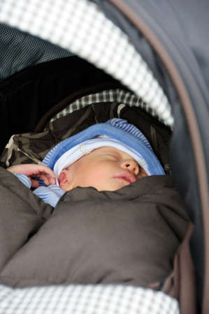 Cute new born baby sleeping in his buggy.