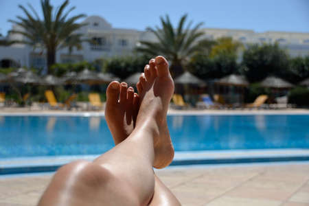 Legs of young woman relaxing at tropical pool.の写真素材