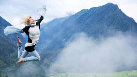 Young beautiful woman jumping at mountain