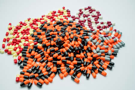 Orange, black, grey, white, red, pale yellow, capsule pills on white backgroundの写真素材