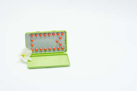 Birth control pills with modern packaging and flower on white backgroundの写真素材