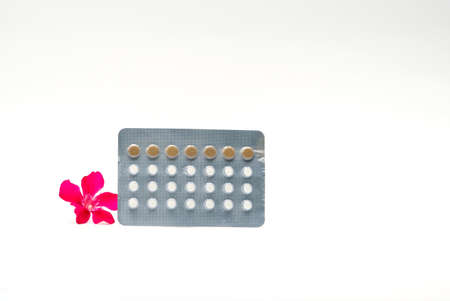Contraceptive pills with pink flower on white backgroundの写真素材