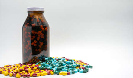 Red, yellow, green, blue antibiotic capsule pills and amber bottle, drug resistanceの写真素材