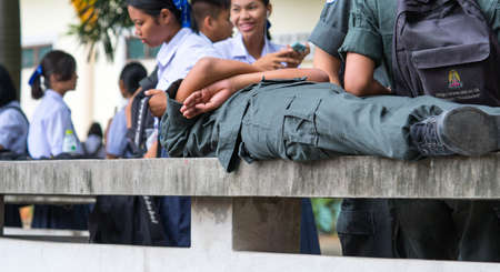 CHONBURI, THAILAND-AUGUST 3, 2017 : Schoolboys wear military students uniform lying on a bench made...