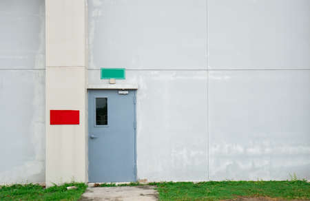 Closed grey door with green and red text box on white concrete wall with copy spaceの写真素材