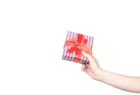 Closeup beautiful and healthy woman hands with neat manicure are holding a Christmas gift box wrapped with red ribbon isolated on white backgroundの写真素材
