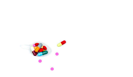 Colorful of tablets and capsules pills in plastic teaspoon and some of them spread on white background with copy space, just add your own text.の写真素材