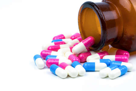 Colorful of antibiotic capsules pills with amber glass bottle isolated on white background. Drug resistance, antibiotic drug use with reasonable, health policy and health insurance concept.の写真素材