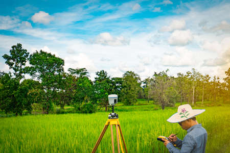 UBONRATCHATHANI, THAILAND-SEPTEMBER 26, 2017 : Asian smart engineer or surveyor is working on controller screen for surveying land in rice field. GPS surveying instrument.のeditorial素材
