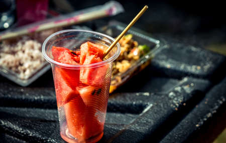 Fresh watermelon slice in clear plastic glass container on black fiber floor of pickup truckの写真素材