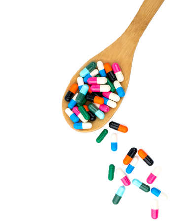Colorful of antibiotics capsule pills in wooden spoon are spilling isolated on white background with copy space and clipping path. Antibiotic drug use with reasonable and health insurance concept.の写真素材