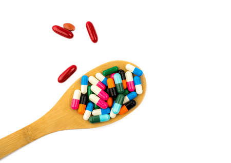 Colorful of capsule pills in wooden spoon are spilling isolated on white background with copy space and clipping path. Antibiotic drug use with reasonable and health insurance concept.の写真素材