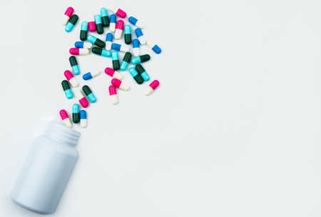 Pouring antibiotics capsule pills into plastic bottle isolated on white background with copy space. Drug storage, antibiotic drug use with reasonable, health policy and health insurance concept.の写真素材