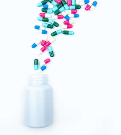 Pouring antibiotics capsule pills into plastic bottle isolated on white background with copy space. Drug storage, antibiotic drug use with reasonable, health policy and health insurance concept.の写真素材