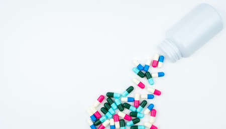 Antibiotic capsules spilling out of pill bottle on white background with copy space, just add your own text. Antibiotic drug use with reasonable concept.の写真素材