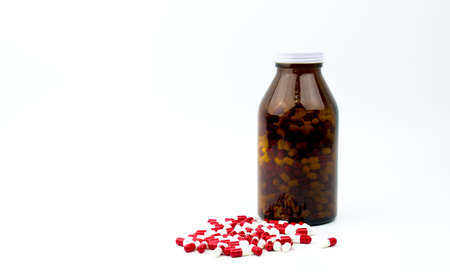 Red, white antibiotic capsules pills and amber glass bottle isolated on white background with copy space and blank label. Drug resistance, antibiotic drug use with reasonable, health policy concept.の写真素材