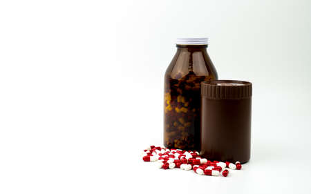 Red, white antibiotic capsules pills and two amber bottles isolated on white background with copy space and blank label. Drug resistance, antibiotic drug use with reasonable, health policy concept.の写真素材