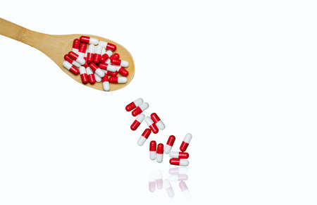 Colorful of antibiotics capsule pills in wooden spoon are spilling isolated on white background with copy space and clipping path. Antibiotic drug use with reasonable and health insurance concept.の写真素材