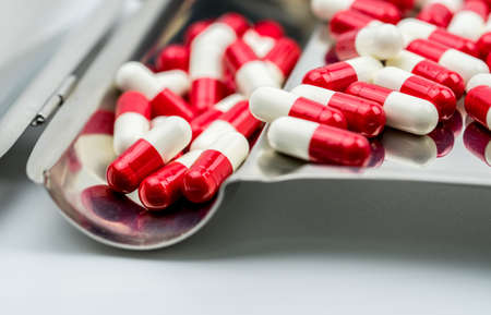 Red, white antibiotic capsules pills on stainless steel drug tray, drug resistance concept. Drug use with reasonable.の写真素材