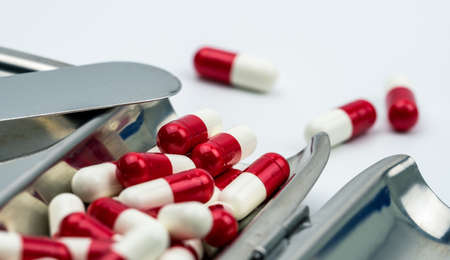 Red, white antibiotic capsules pills on stainless steel drug tray, drug resistance concept. Drug use with reasonable.の写真素材