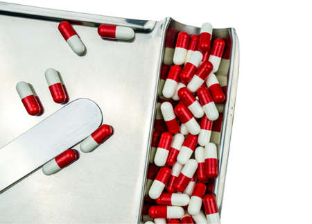 Top view of red, white antibiotic capsules pills isolated on stainless steel drug tray with clipping path, drug resistance concept. Drug use with reasonable.の写真素材