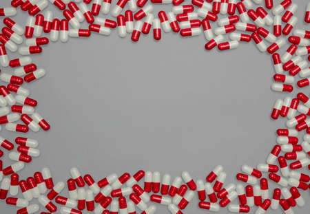 Red, white antibiotic capsules pills on grey background with copy space. Drug resistance, antibiotic drug use with reasonable, health policy and health insurance concept.の写真素材