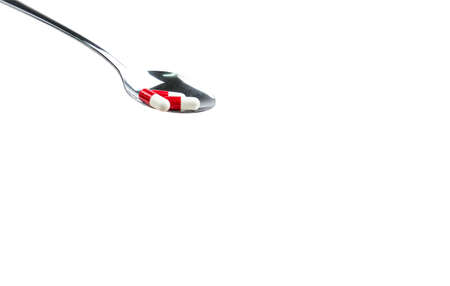 Antibiotic capsule pills in stainless steel spoon isolated on background with copy space and clipping path. Drug resistance concept. Antibiotics drug use with reasonable and global healthcare concept.の写真素材