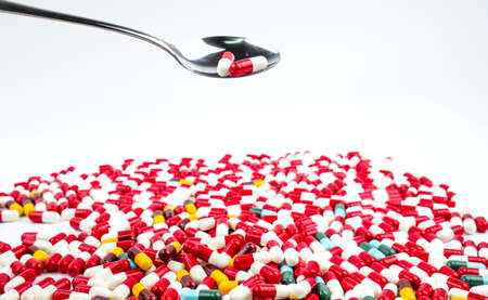 Antibiotic capsules pills in stainless steel spoon on white background with copy space. Drug resistance concept. Antibiotics drug use with reasonable and global healthcare concept.の写真素材