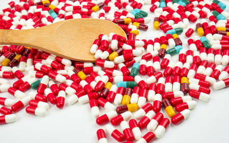 Colorful of antibiotic capsules pills and wood spoon on white background. Drug resistance concept. Antibiotics drug use with reasonable and global healthcare concept.の写真素材