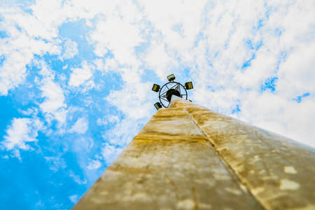 Sport lights of the stadium with rusty pole on beautiful blue sky and white cumulus with copy space for text.の写真素材