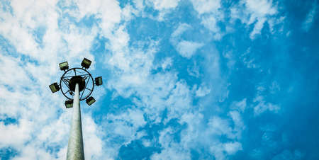 Sport lights of the stadium with pole on beautiful blue sky and white cumulus clouds with copy space for text.の写真素材