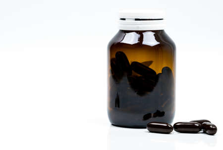 Multivitamins capsule pills for pregnant woman with amber bottle with blank label and copy space isolated on white background. Vitamins and supplements for hard working guy. Global healthcare conceptの写真素材