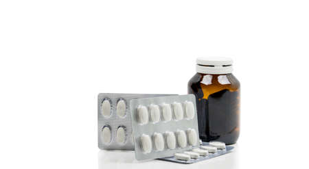 Vitamins capsule in amber glass bottle with blank label and supplements tablets in blister pack on white background. Antioxidants for healthy skin. Good supplement pills for woman bone.の写真素材