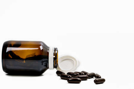 Multivitamins capsule pills for pregnant woman with amber bottle with blank label and copy space isolated on white background. Vitamins and supplements for hard working guy. Global healthcare conceptの写真素材
