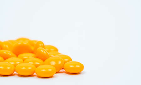 Yellow sugar coated tablets pills on white background with copy space. Medicine for treatment constipation.の写真素材