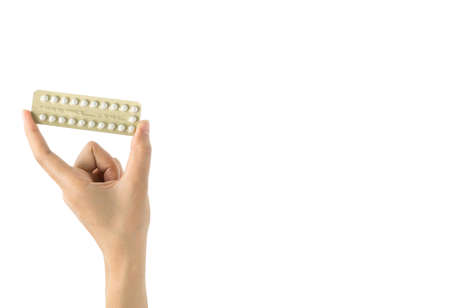 Asian young woman holding pack of contraceptive pills with one hand isolated on white background with copy space and clipping path. Choosing family planning with birth control pill conceptの写真素材