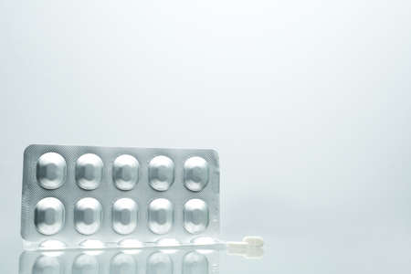 Silver aluminium foil blister pack of pills with 2 white tablet pills on white background with...