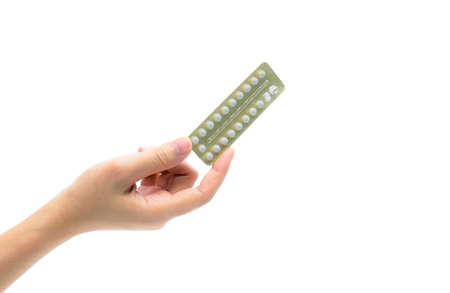 Woman hand taking birth control pills. Asian adult woman holding pack of contraceptive pills isolated on white backgroundの写真素材