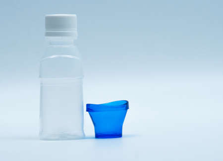 Sterile eye lotion in white plastic bottle with blue eyebath and copy space and blank label. Eye wash after contact pollution environment or after swimming in chlorine contaminate pool.の写真素材