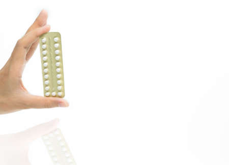 Woman hand taking birth control pills. Asian adult woman holding pack of contraceptive pills isolated on white background with clipping path. Choosing family planning with birth control pills conceptの写真素材