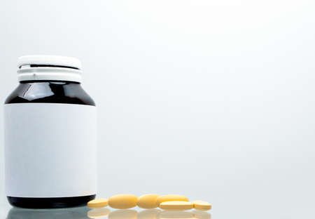 Tablets pills of vitamin C 1,000 mg on white background and amber bottle with blank label and copy space for text. Vitamin and supplement concept. Antioxidantの写真素材