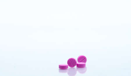 Macro shot of four small pink tablets pills isolated on white background with copy space for text. Medicine for asthma treatment conceptの写真素材