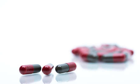 Macro shot detail selective focus of red and grey capsule pills on blurred casules background with copy space for text.の写真素材