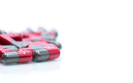 Macro shot detail selective focus of red and grey capsule pills isolated on white background with copy space for text. Migraine prophylaxis treatment concept.の写真素材
