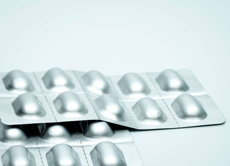 Tablet pills in silver aluminium blister pack packaging on blurred background of pack of pills with copy spaceの写真素材